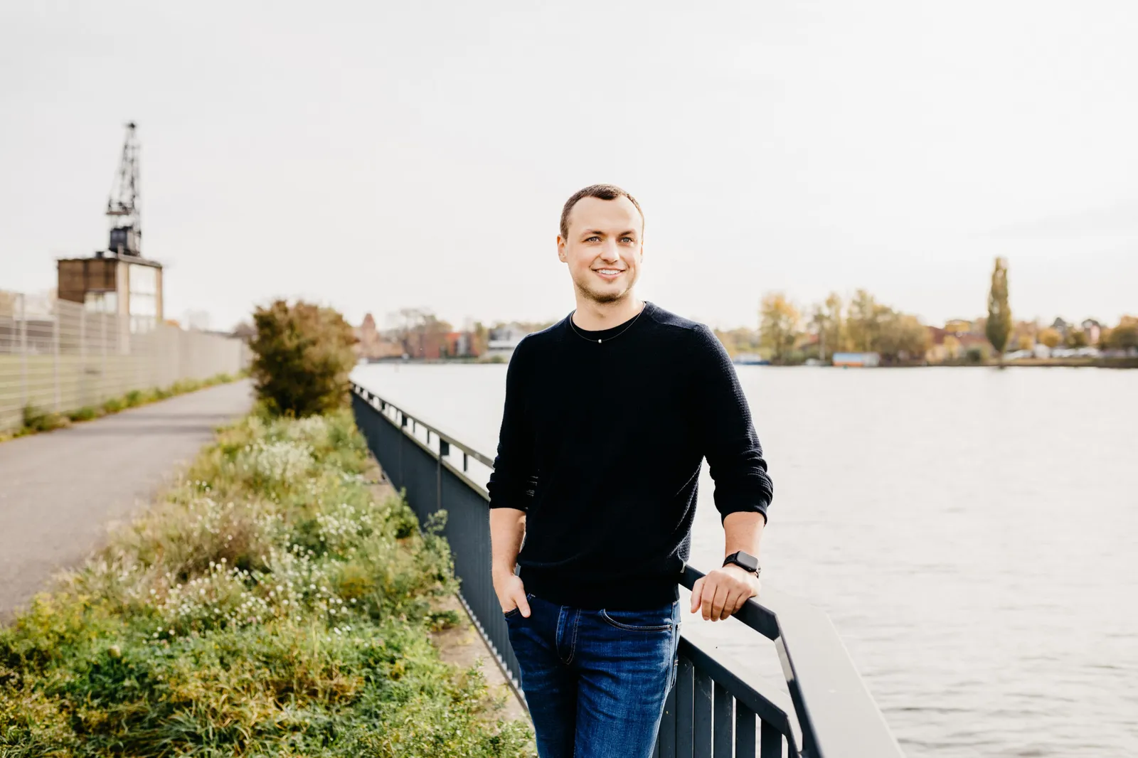 Timo Maletschek am Wasser, lächelnd in schwarzem Pullover